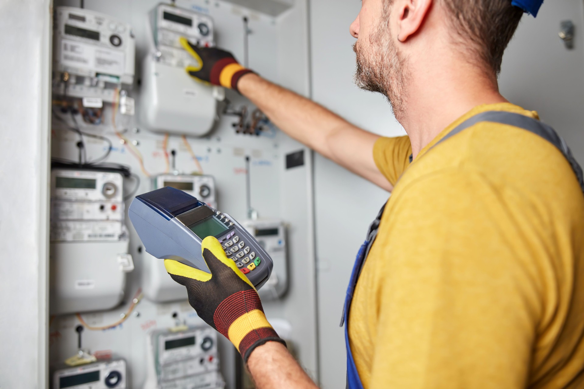 Technician reading consumption and charging on a wireless electricity power meter station in a building.